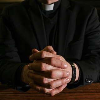 Das Symbolfoto zeigt einen Priester, er kniet in einer Kirche und hat die Hände fest zum Gebet gefaltet. In Koblenz beginnt das Berufungsverfahren gegen einen umstrittenen katholischen Priester aus dem Westerwald, dem Kindesmissbrauch vorgeworfen wird.