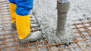 Bauarbeiter betonieren das Fundament von einem neuen Gebäude (Symbolbild).
