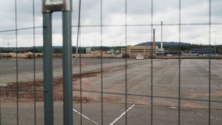 Blick durch einen Bauzaun auf die stillliegende Baustelle der ACC-Batteriefabrick in Kaiserslautern