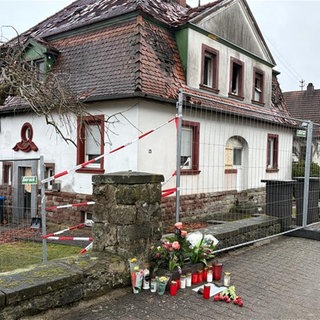 Blumen und Kerzen vor dem Haus in Hermersberg, in dem zwei Menschen bei einem Brand gestorben waren