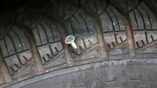 Ein Nagel steckt in einem Autoreifen