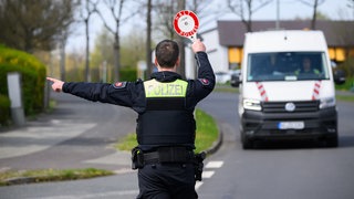 Ein Polizist winkt den Fahrer eines Transporters nach einem Geschwindigkeitsvergehen aus dem Verkehr.