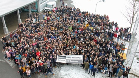 Schülerinnen und Schüler des Gymnasiums am Rittersberg in Kaiserslautern halten gemeinsam ein Banner zu "Schule ohne Rassismus – Schule mit Courage". Seit 2019 trägt das Gymnasium diesen Titel und ist damit Teil des bundesweiten Schul-Netzwerks gegen Rassismus und Diskriminierung.