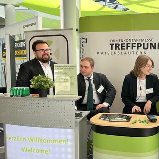 Studierende der RPTU haben die Jobmesse Treffpunkt organisiert, zu Ihnen zählen Sina Gebhardt (r.) und Joshua Cooley (l.). (Menschen stehen an einem Messestand