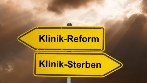 Ein Wegweiser, der Pfeil zeigt nach links zur Klinikreform, nach rechts zum Klinik-Sterben