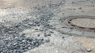 Eine Straße mit Löchern und Splitt (Symbolbild).