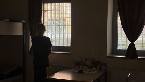 Eine Jugendliche steht vor einem Fenster in der JVA Zweibrücken. 
