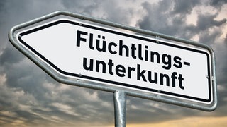 Hinweisschild zu einer Flüchtlingsunterkunft - in Isert im Westerwald gibt es Kritik an der geplanten Flüchtlingsunterbringung.