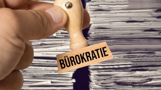 Bürokratie-Stempel vor Aktenhaufen