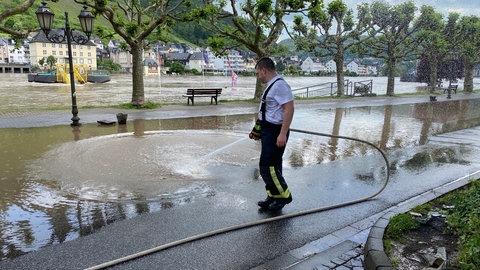 Ein Mann spritzt mit einem Schlauch die verschlammte Uferpromenade ab. Die Aufräumarbeiten nach dem Hochwasser sind in Cochem abgeschlossen. 