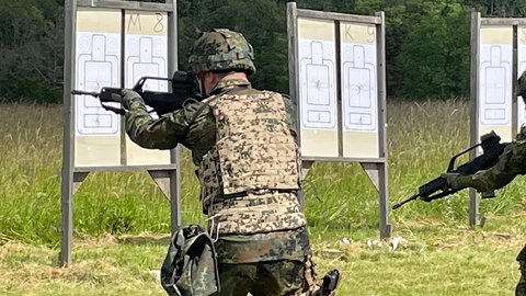Mann in Tarnuniform schießt mit Sturmgewehr
