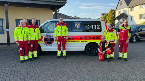 Mehrere Mitglieder des Vereins RescueGroup e. V. vor ihrem Einsatzwagen: Sie werden in der Verbandsgemeinde Bad Marienberg mitalarmiert, wenn ein Rettungswagen mit Blaulicht ausrückt. Dann fahren sie als freiwillige Ersthelfer selbst vor Ort und sind oft schneller als der Notarzt da, um zu helfen.