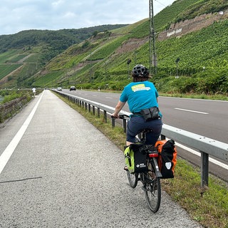 Eine Radfahrerin fährt am Rhein entlang Richtung Boppard