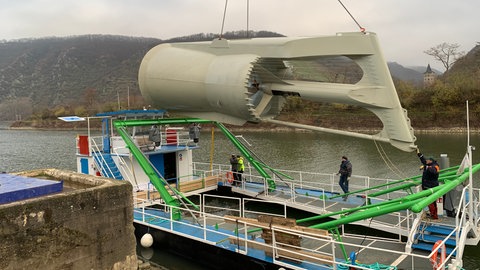 Die Strom-Boje hängt an einem Kran über einem Schiff 