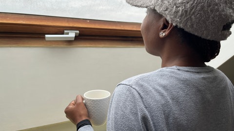 Lisa (Name geändert) schaut mit einer Kaffeetasse in der Hand aus dem Fenster ihrer "Second Stage"-Wohnung. Sie wohnt hier nur übergangsweise. Nach fünf Monaten im Frauenhaus Koblenz hat sie hier jetzt ihr eigenes Reich und lernt Schritt für Schritt, wieder auf eigenen Füßen zu stehen.