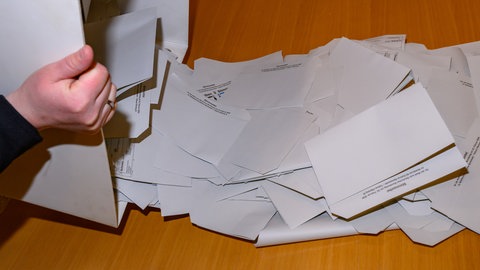 Wahlunterlagen werden in einem Wahllokal ausgezählt. VG Nastätten kritisiert, dass die Stimmen der Briefwähler nur auf VG Ebene zugeordnet werden.