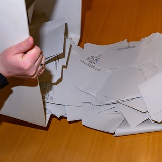 Wahlunterlagen werden in einem Wahllokal ausgezählt. VG Nastätten kritisiert, dass die Stimmen der Briefwähler nur auf VG Ebene zugeordnet werden.