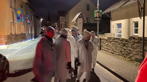 Die Glockenmänner von Heimbach-Weis ziehen frühmorgens mit weißen Nachthemden im Dunkeln und glockenschlagend durch die Straßen.
