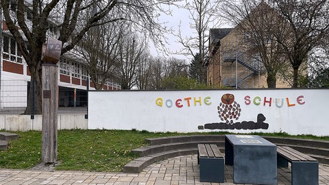 Schild mit Aufschrift Goethe-Schule vor mehreren Gebäuden. 