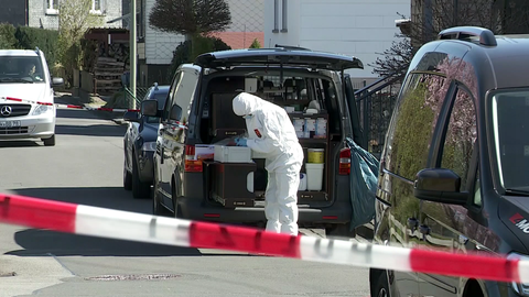 Ein Mitarbeiter der Spurensicherung steht in Weitefeld (Landkreis Altenkirchen) vor dem Haus, in dem eine dreiköpfige Familie getötet wurde. Die Polizei sucht weiter nach dem Tatverdächtigen.