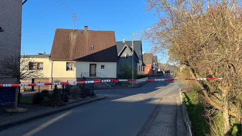 Ein rot-weißes Polizeiband sperrt den Tatort in Weitefeld im Westerwald ab. Laut dem Bürgermeister sind alle Sportveranstaltungen in dem Ort abgesagt.