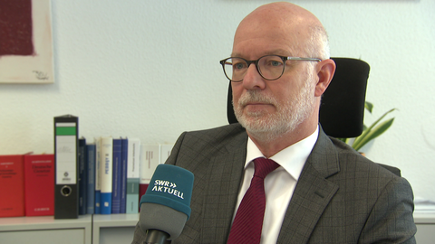 Nach dem gewaltsamen Tod einer Familie in Weitefeld im Kreis Altenkirchen fahndet die Polizei nach wie vor nach dem mutmaßlichen Täter. Der zuständige Oberstaatsanwalt Mario Mannweiler bestätigte im SWR-Gespräch eine frühere Haftstrafe des Gesuchten.