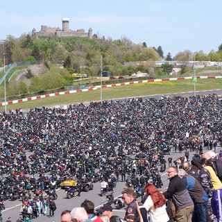 Viele tausend Menschen stehen auf der Rennstrecke Nürburgring. Im Hintergrund die Ruine der Nürburg