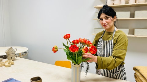 Liana Sulejmanova sortiert Blumen in einer selbstgetöpferten Vase. Sie hat sich in Kaiserslautern mit einem Töpfercafé einen Traum verwirklicht.