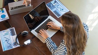 Frau sitzt am Laptop. 
