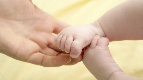 Eine Hand hält Babyfüße.