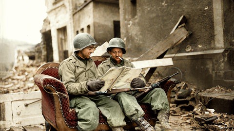 Zwei US-Soldaten sitzen nach dem 2. Weltkrieg in den Trümmern von Koblenz auf einem Sofa auf der Straße