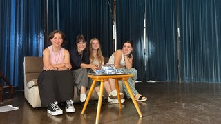 Fünf Schülerinnen sitzen auf einem Sofa auf der Bühne. Sie haben ein Theaterstück für den Hospizverein Rhein-Ahr-Eifel geschrieben.
