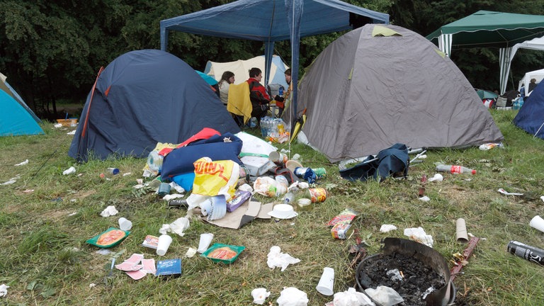 Immer wieder ein Thema - der viele Müll, den die Besucher des Festivals Rock am Ring hinterlassen. Diese Fans frühstücken im Juni 2009 auf dem Campinggelände am Nürburgring hinter Müllbergen.