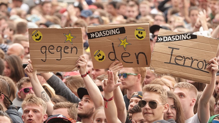 Junge Menschen halten bei Rock am Ring 2017 Schilder mit der Aufschrift "gegen den Terror" in die Höhe: Das Festival war wegen einer Terrorwarnung zeitweise unterbrochen worden.