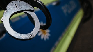 Handschellen vor einem Polizeiauto - ein Mann aus Bad Breisig wurde festgenommen wegen eines Cold Cases