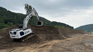 Ein Bagger schaufelt Geröll von der Flutkatastrophe weg.