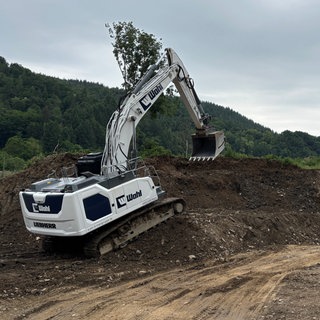Ein Bagger schaufelt Geröll von der Flutkatastrophe weg.
