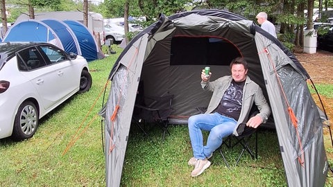 Rainer sitzt zufrieden im gemieteten Zelt auf dem Campingplatz