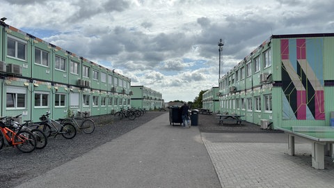 Rechts und links auf dem Bild sieht man aufeinandergestapelte Container, in denen die Schülerinnen und Schüler des Are-Gymnasiums unterrichtet werden.