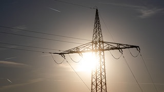 Ein Strommast wird von der Sonne angestrahlt. Verursachen hohe Temperaturen Stromausfälle?