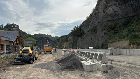 Zwei Baumaschinen stehen am Bahnhof in Ahrbrück, wo gerade Bahngleise neu gebaut werden.