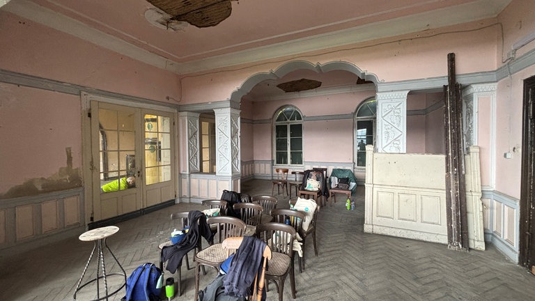 Im alten Speisesaal stehen Stühle auf denen die Arbeiter ihre Sachen abgelegt haben. An den Bögen der Durchgänge sind die für das Hotel typischen Verzierungen zu sehen. 