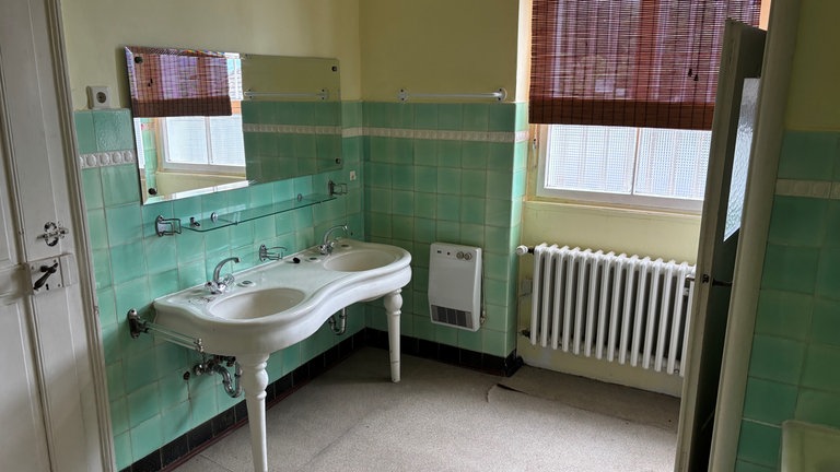 Ein altes grün gefliestes Badezimmer.