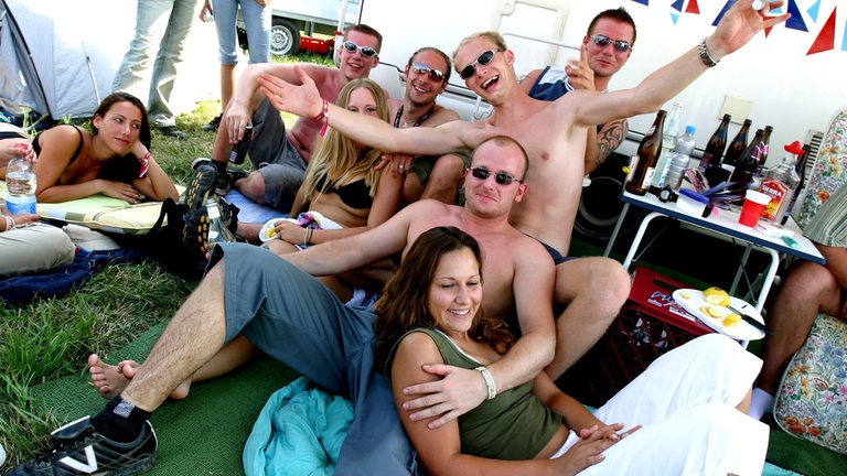 Besucherinnen und Besucher der Nature One 2003 feiern ausgelassen auf dem Campinggelände.