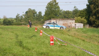 Polizistin sichert den Fundort der Leiche auf einer Wiese außerhalb von Weitefeld