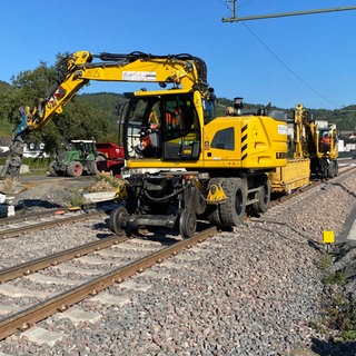 Ein gelber Bagger arbeitet an der Ahrtalbahn in Dernau: Bald soll die Züge wieder durchgängig zwischen Remagen und Ahrbrück fahren können. 