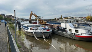 Baggerschiff lädt Fracht von beschädigtem Schiff um.