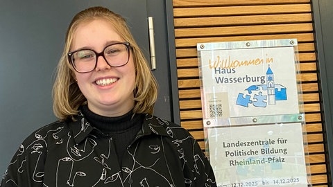Sophie Röller neben dem Schild Haus Wasserburg in Vallendar. Dort hat sich die Redaktion des Wahl-O-Mat getroffen. 