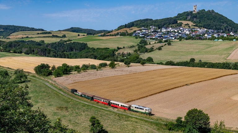 Auf der Brohltalbahn ist Diesellok D5 mit dem Vulkan-Express an der Burgruine Ohlbrück unterwegs.
