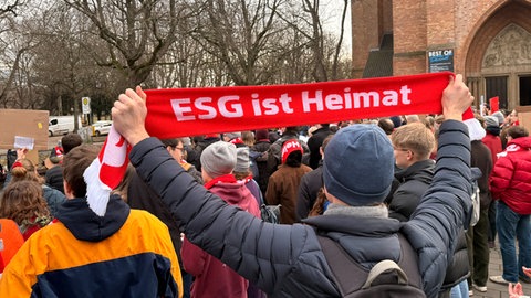 Ein Demonstrant hält einen Schal hoch mit der Aufschrift "ESG ist Heimat".
